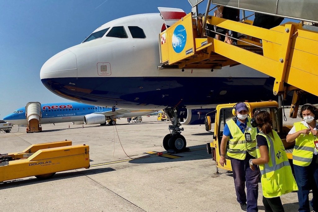 Plane being loaded at Verona Airport. Baggage handlers and staff.